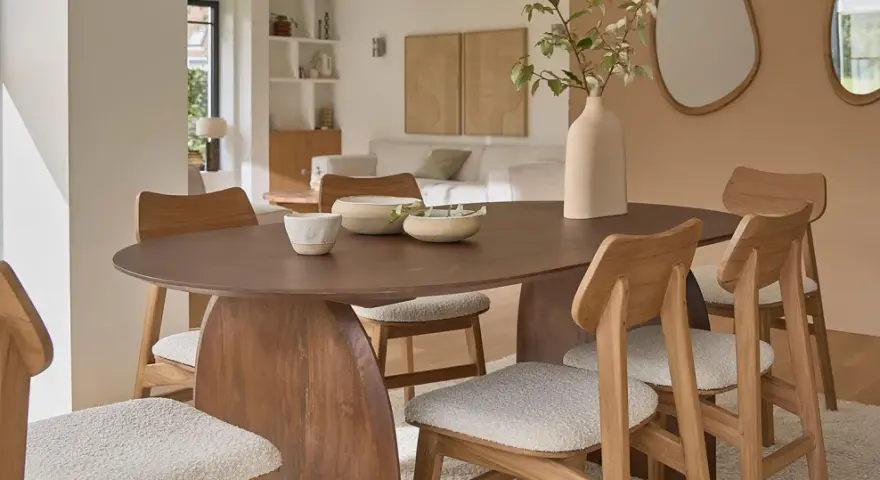 Table et chaises en bois mindi dans une salle à manger lumineuse. Des bols décoratifs et une plante apportent une touche naturelle.