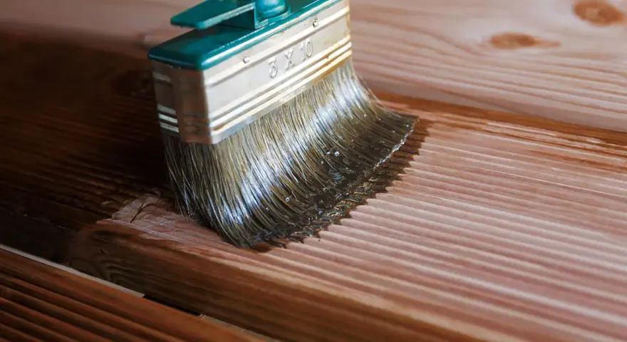 Application d'une lasure sur des lames de bois de douglas. La brosse dépose le produit sur le bois, le protégeant et le sublimant.