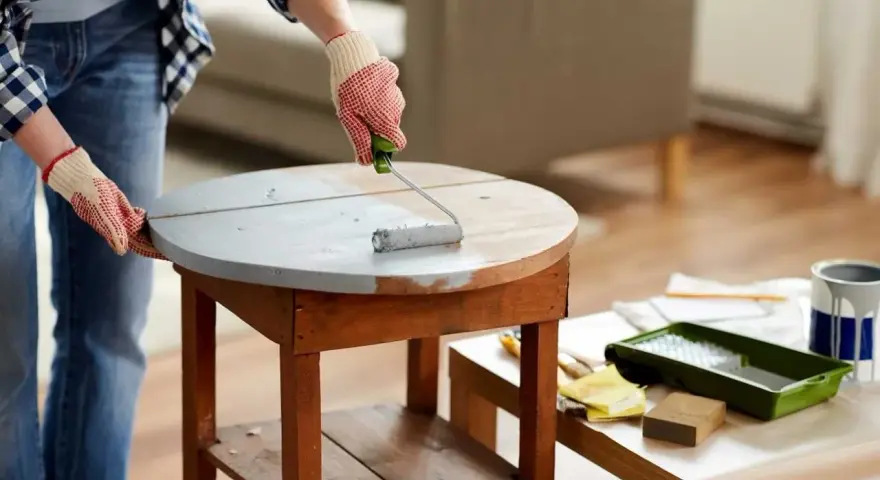 Application d'une sous-couche grise sur une table en bois. Le résultat avant/après du decapant bois est visible.