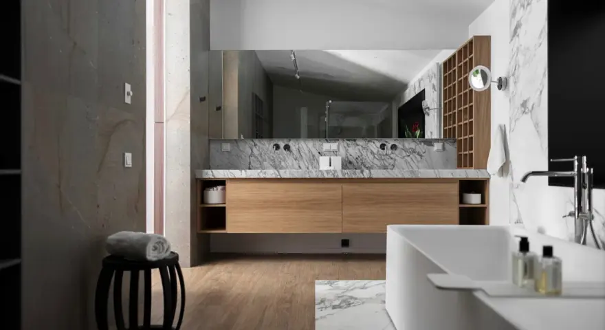 Salle de bain moderne avec meuble en bois clair, marbre et baignoire. Le bois est un excellent choix pour le meuble de salle de bain, alliant esthétique et durabilité.