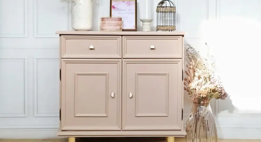 Meuble vintage repeint en rose poudré, prêt à peindre sur ancienne peinture bois. Décoré de fleurs séchées et d'une cage décorative.