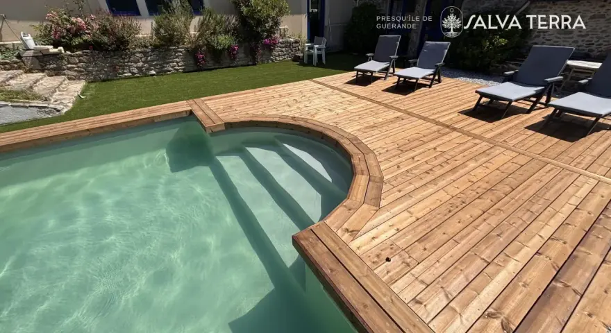 Terrasse en bois autour d'une piscine avec des chaises longues.