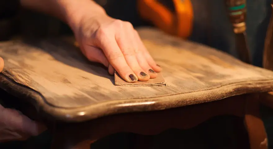 Main poncée pour enlever vernis bois. Le bicarbonate de soude peut aider à décaper.