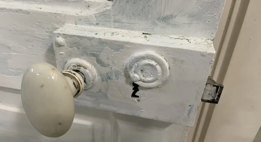 Poignée de porte ancienne et serrure en cours de préparation pour décaper une porte en bois peinte.