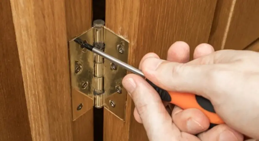 Réglage d'une charnière de porte de placard en bois avec un tournevis. Quelle charnière pour porte placard choisir ?