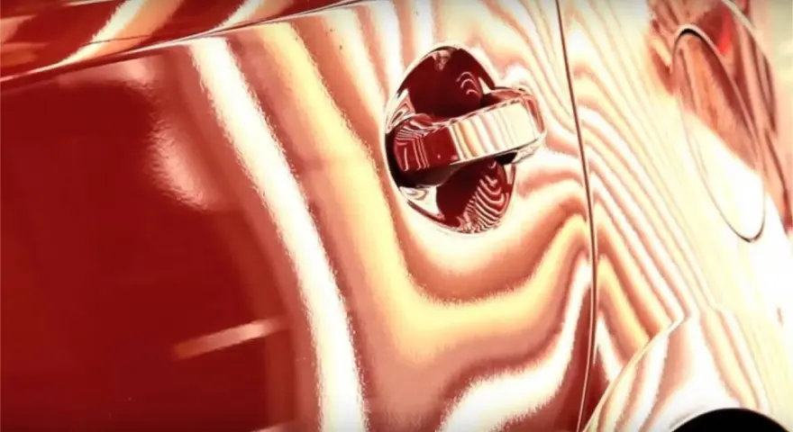 La peinture rouge d'une voiture présente des reflets ondulés, comme pour supprimer l'effet peau d'orange.