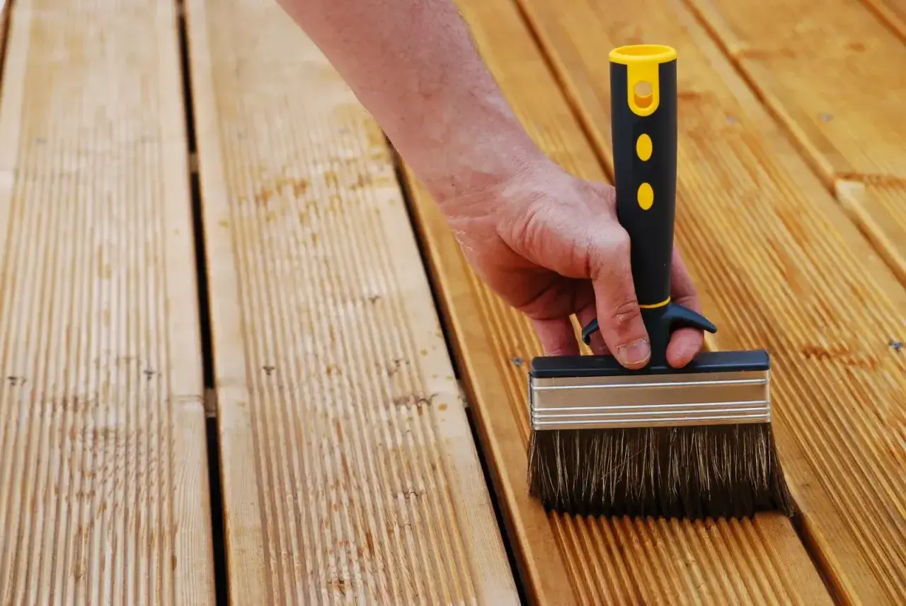 Main tenant enlever saturateur bois avec une large brosse. Le bois est clair et rainur&eacute;.