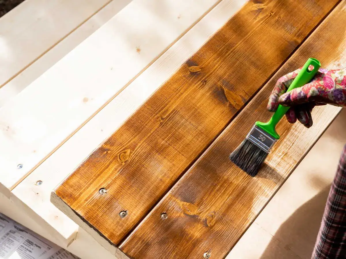 Application d'une lasure sur des planches de bois pour une protection durable.