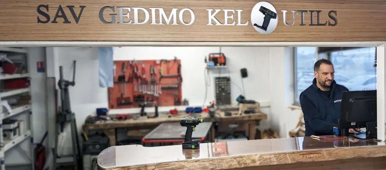 Un technicien s'occupe de la réparation d'outillage électroportatif dans un atelier.
