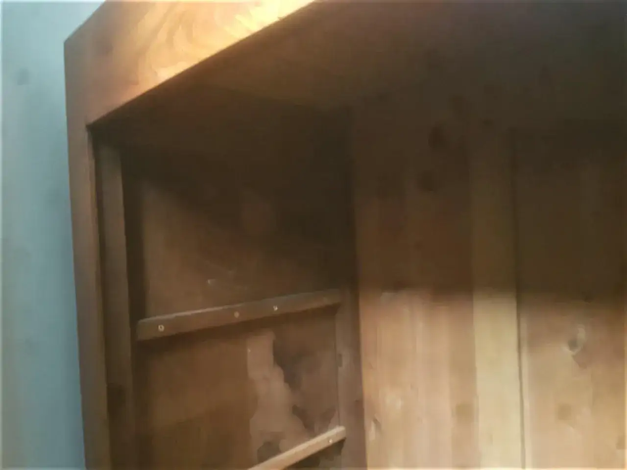 Intérieur d'une armoire ancienne en bois, prête à démonter. Les étagères sont visibles, ainsi que les marques du temps.