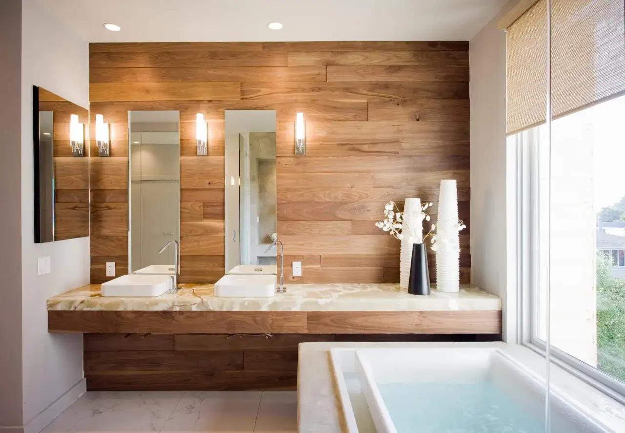 Salle de bain moderne avec murs en bois, lavabos, baignoire et une belle finition pour prot&eacute;ger un meuble en bois de l'eau.