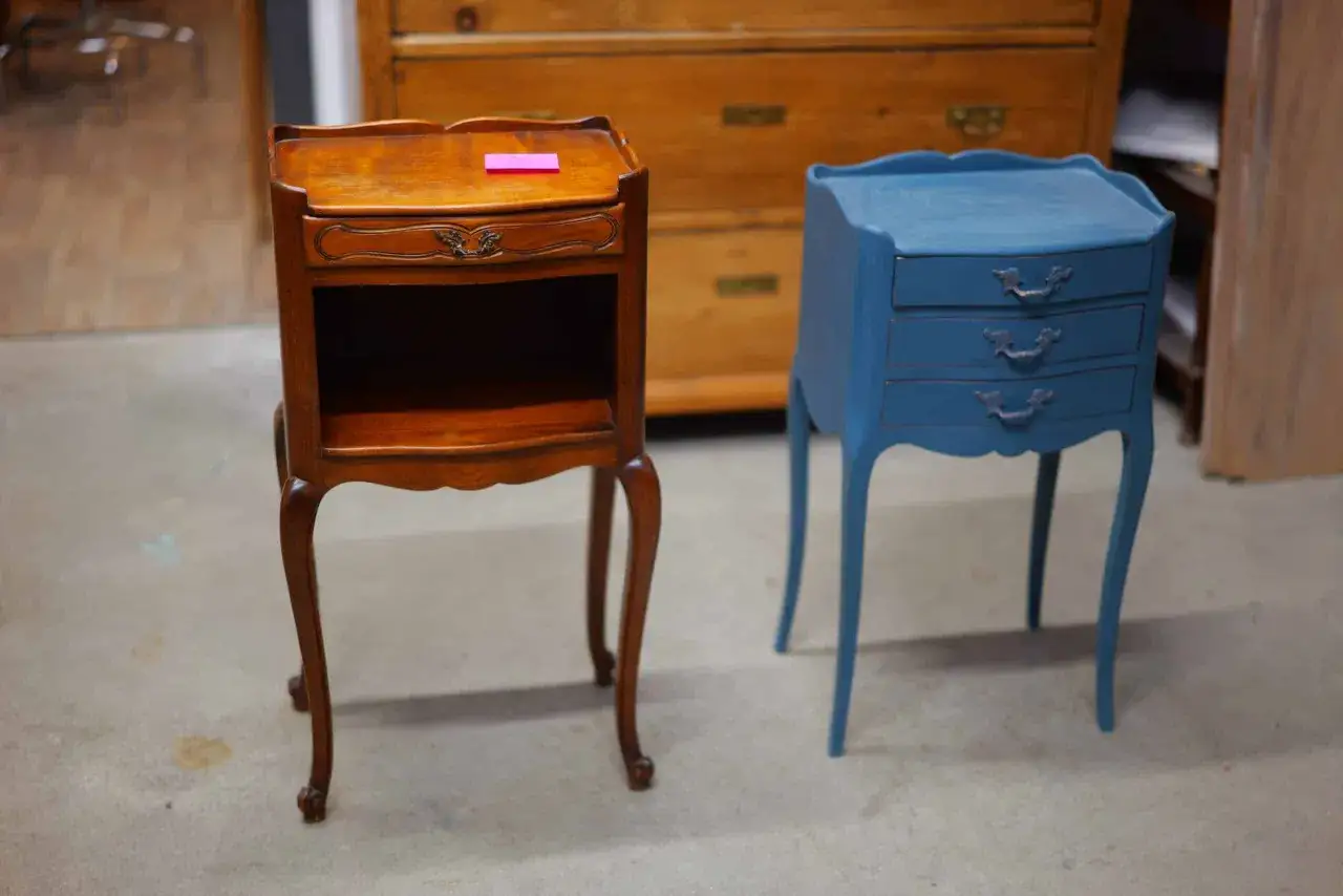 Deux petites tables de chevet, l'une en bois verni, l'autre peinte en bleu, illustrent le processus de restauration meuble ancien.