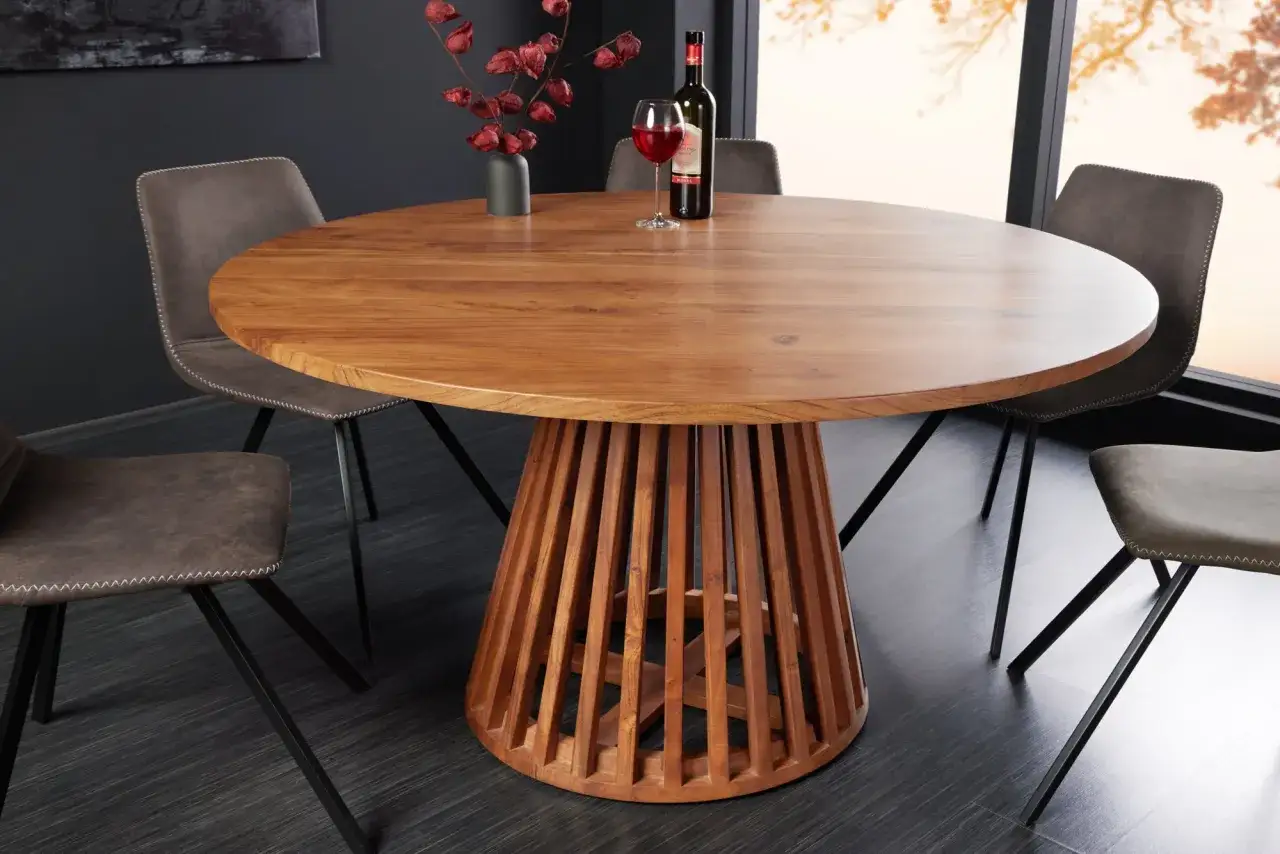 Table ronde en acacia pour un entretien facile à l'intérieur. Un verre de vin rouge et une bouteille sur la table, entourée de chaises modernes.
