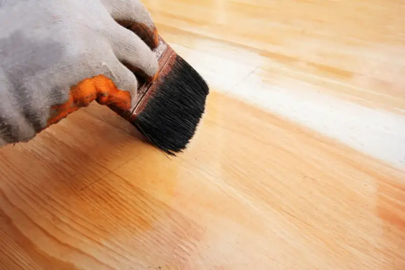Application d'un vernis protecteur pour le traitement plan de travail bois. La brosse dépose une couche uniforme sur le bois clair.