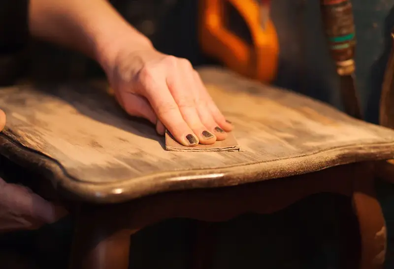 Main poncée pour enlever vernis bois. Le bicarbonate de soude peut aider à décaper.